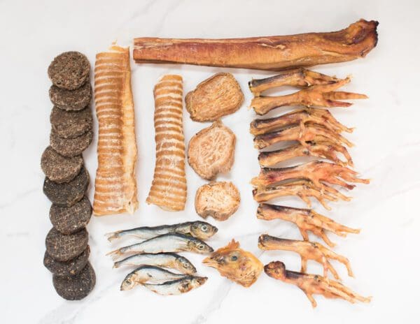 A variety of Bully Stick (1) dog treats and dried meats on a marble table.